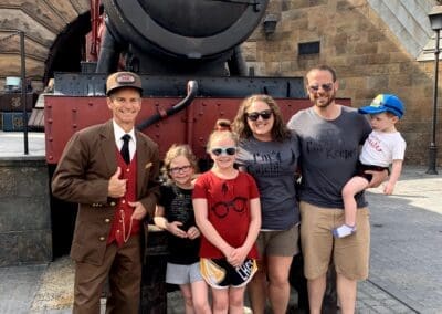 Family posing with a train conductor at a theme park, showcasing a memorable vacation experience, highlighting travel planning insights for Disney destinations.