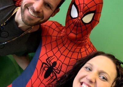 Couple posing with Spider-Man character at a theme park, smiling and enjoying a fun moment.