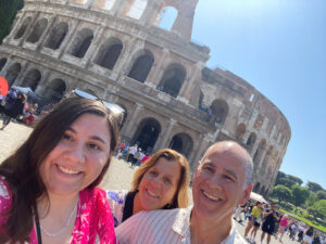 AnaDProfile Group selfie in front of the Colosseum in Rome, capturing joyful travelers enjoying their vacation experience.